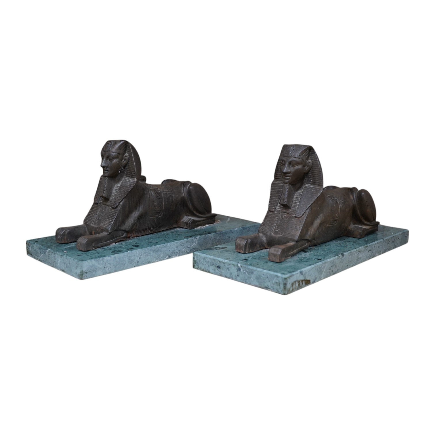 A pair of bronze models of Sphinxes, raised on green serpentine marble bases, 32cm long. Condition - fair, both detached from bases